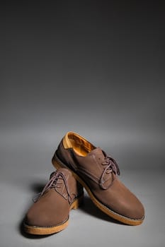 Brown suede shoes on a grey background with vertical copy space.