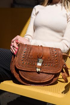 small brown women's leather bag with a carved pattern. street photo