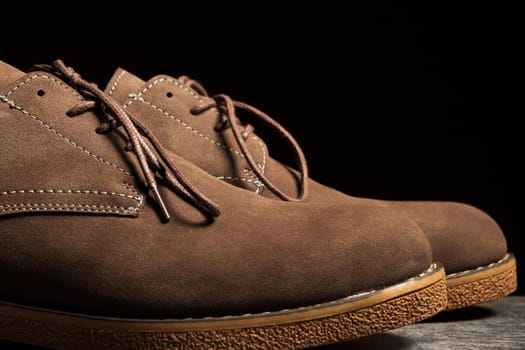 Brown shoes with laces on a black background. Side view, close-up.