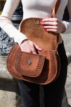 open small brown women's leather bag with a carved pattern. street photo