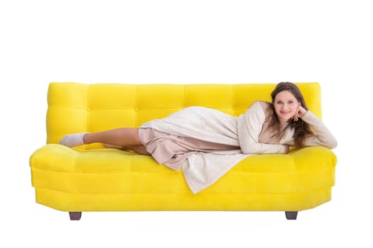 Young smiling caucasian woman lies on a yellow couch, look at camera, isolated on white.