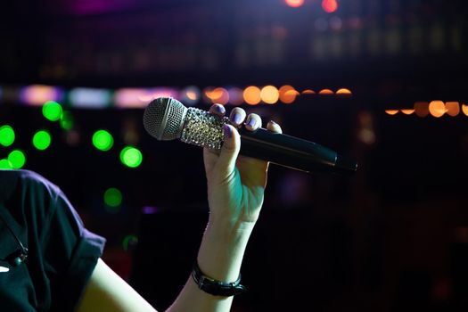 Wireless microphone with rhinestones in woman hand on the night club stage.