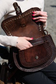 open small brown women's leather bag with a carved pattern. street photo