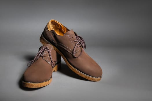 Brown suede shoes with laces on a grey background with copy space.