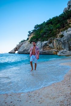 Golfo di Orosei Sardina, Men on the beach Sardinia Italy, young guy on vacation Sardinia Italy, man playing in the ocean with crystal clear blue water, . High quality photo