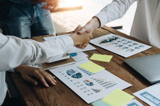 Group business people handshake at meeting table in office together. Young businessman and businesswoman workers express agreement of investment deal