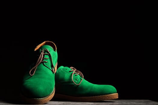 Concert green shoes with laces on a black background with copy space.