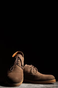 Brown shoes on a black background with vertical copy space.