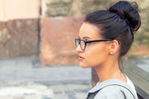Side view portrait of young brunette business woman wearing eyeglasses outdoors