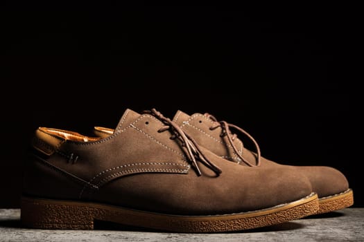 Side view of brown shoes with laces on a black background.