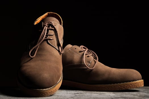 Brown shoes with laces on a black background.