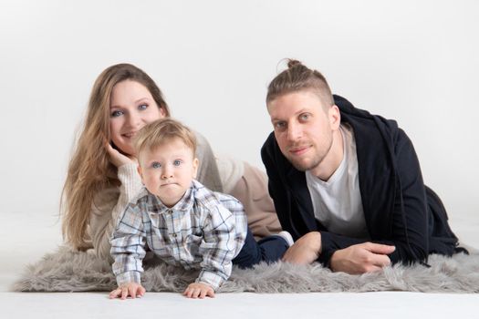 Portrait of young caucasian parents with little curious baby.