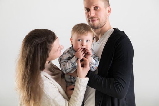 Young happy parents with their baby in the spotlight on white background.