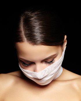 Beautiful woman with a bandage mask on face. Fashion eye make-up. Beauty plastic surgery or protection hygiene in viral covid-19 pandemic