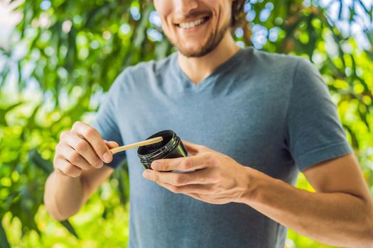 Young man brush teeth using Activated charcoal powder for brushing and whitening teeth. Bamboo eco brush.