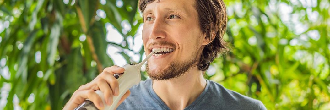 Young man uses an oral irrigator to brush his teeth. BANNER, LONG FORMAT