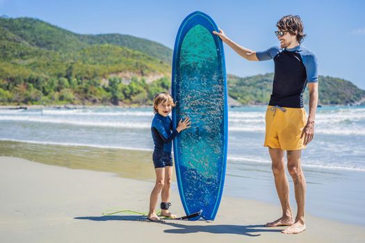Father or instructor teaching his son how to surf in the sea on vacation or holiday. Travel and sports with children concept. Surfing lesson for kids.