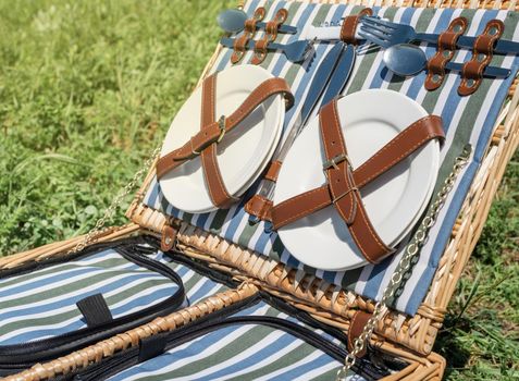 Closeup of picnic basket with drinks and food on the grass. Nice picnic on sunny summer day, fun and leisure