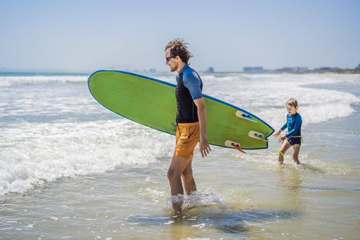 Father or instructor teaching his son how to surf in the sea on vacation or holiday. Travel and sports with children concept. Surfing lesson for kids.