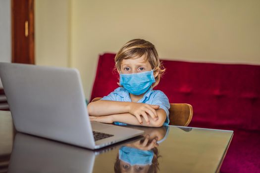 Boy studying online at home using laptop in medical masks to protect against coronovirus. Studying during quarantine. Global pandemic covid19 virus.