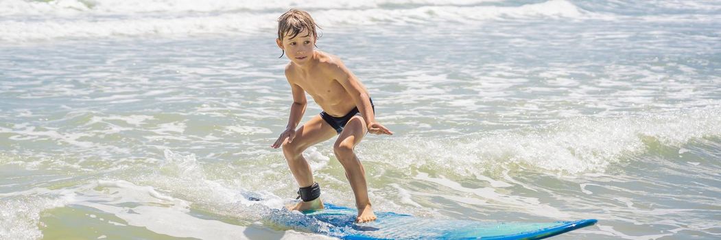 Healthy young boy learning to surf in the sea or ocean. BANNER, LONG FORMAT