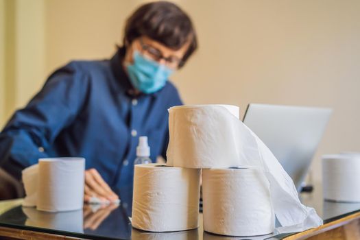 Coronavirus. Man working from home wearing protective mask. quarantine for coronavirus wearing protective mask. Working from home. Cleaning with sanitizer gel. Bought a lot of toilet paper.