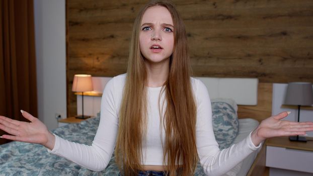 Annoyed young woman in white blouse raising hands in anger and shouting what why how, quarreling scolding for troubles, mad about problems. Girl scolding with indignant expression, blaming in defeat