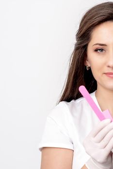 Portrait of beautiful young caucasian woman manicure master holding manicure tools on white background