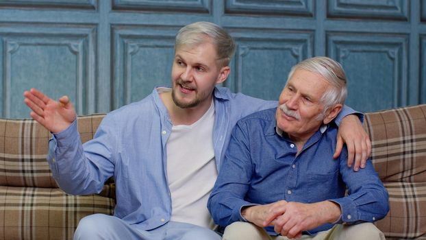 Cheerful bonding loving different male generations family of senior father and adult son or grandson having heart-to-heart conversation. Young man with gray-haired old dad or grandfather. Good friends