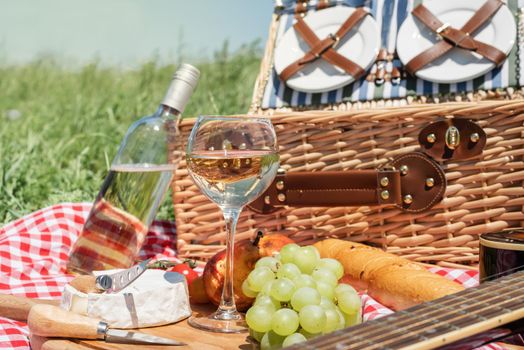 Closeup of picnic basket with drinks and food on the grass. Nice picnic on sunny summer day, fun and leisure
