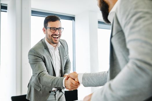 portrait of a young business man offering hand shaking hands introducing in the office