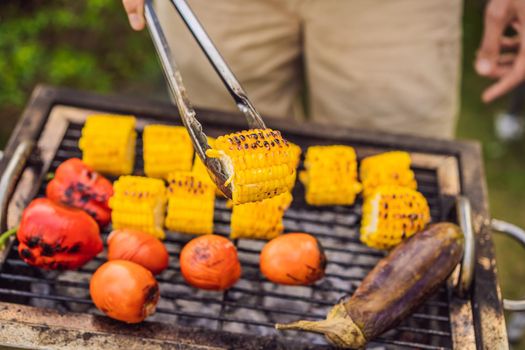 Man with tongs cooking on a back yard barbecue.