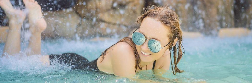 Young joyful woman under the water stream, pool, day spa, hot springs. BANNER, LONG FORMAT