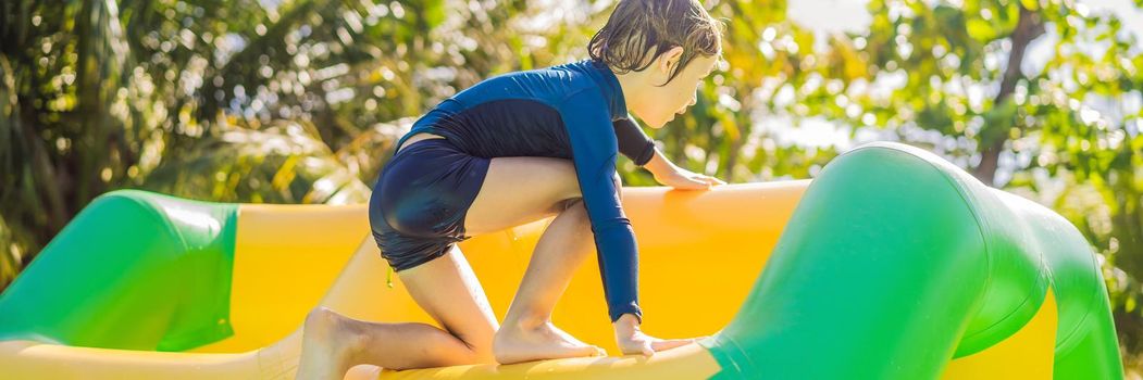 Cute boy runs an inflatable obstacle course in the pool. BANNER, LONG FORMAT