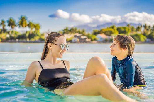 Luxury resort swimming pool. Happy family tourists relaxing in holiday retreat on summer travel vacation enjoying ocean background.