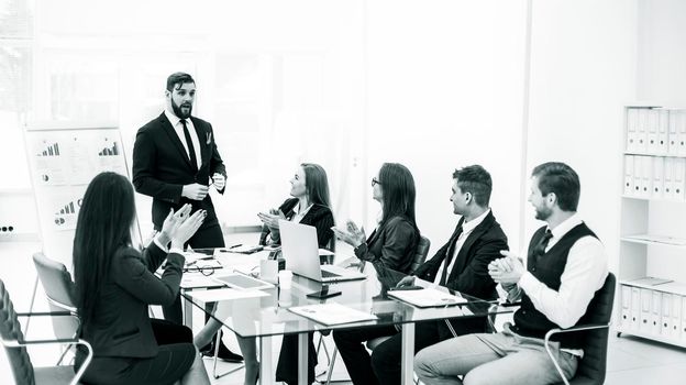 black-and-white photo:successful business team applauding the Manager Finance on the presentation of the new project in the workplace in the office
