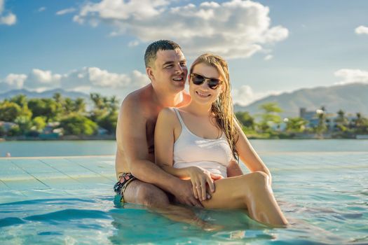 Luxury resort swimming pool. Happy couple tourists relaxing in holiday retreat on summer travel vacation enjoying ocean background.