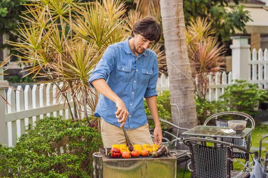 Man with tongs cooking on a back yard barbecue.