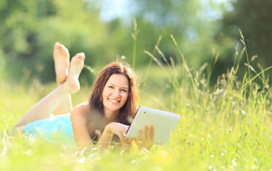 Happy woman reading e-book in the park