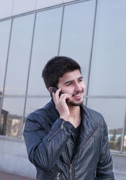 modern young man talking on a mobile phone on the street