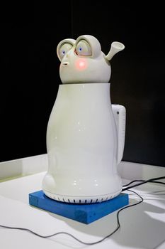Emotional white robot, similar to an electric kettle, at the exhibition of robots. Almaty, Kazakhstan - February 19, 2022