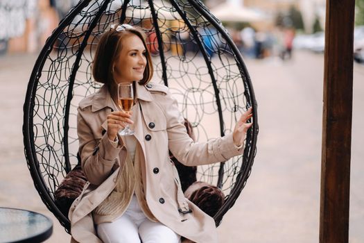 A happy stylish girl In a gray coat walks around the city.