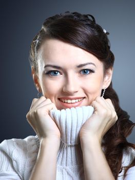 Beautiful girl smiles in a sweater. Isolated on a gray background.