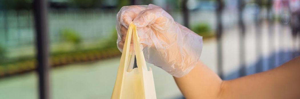 Woman hands in medical protective gloves hold package with purchases. BANNER, LONG FORMAT