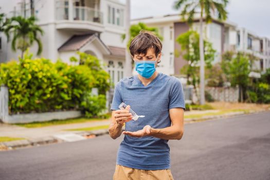 Man in a small town in a medical mask uses a sanitizer because of a coronovirus epidemic.