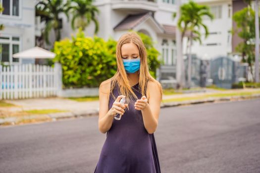 Woman in a small town in a medical mask uses a sanitizer because of a coronovirus epidemic.