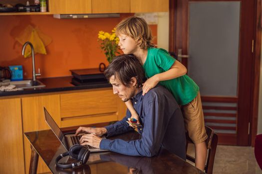 Man is trying to work from home because of the coronovirus epidemic, but his son is stopping him. Self-isolation at home. Children at home schooling. Parents at remote work. Quarantine, self-isolation, coronavirus.