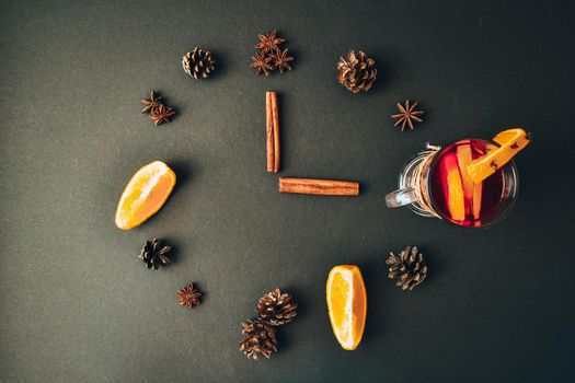 A clock in the form of spice for mulled wine on black background. Cinnamon sticks, anise stars, pine cones, slice of orange. Concept, creative work. Top view. Holiday atmosphere, Rustic style. The idea for creating greeting cards