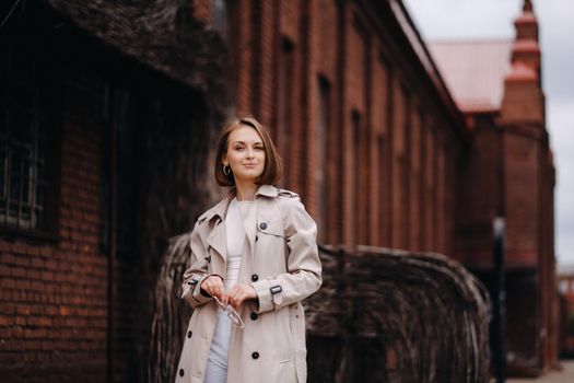 A happy stylish girl in a gray coat walks around the city.