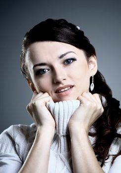 Beautiful girl smiles in a sweater. Isolated on a gray background.